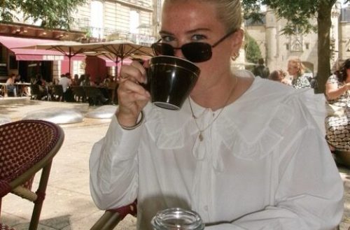 Mae Legare drinking coffee at an outdoor cafe.